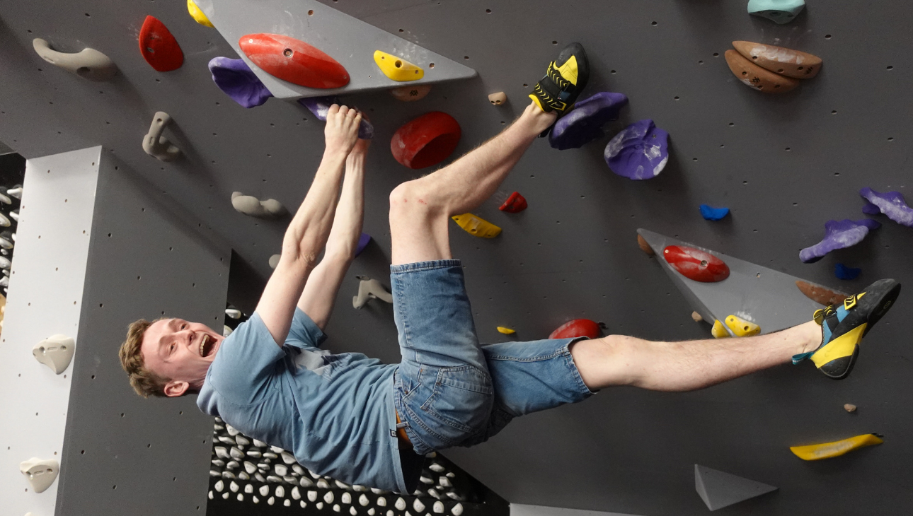 A man climbing an overhanging boulder at The Climbing Hangar