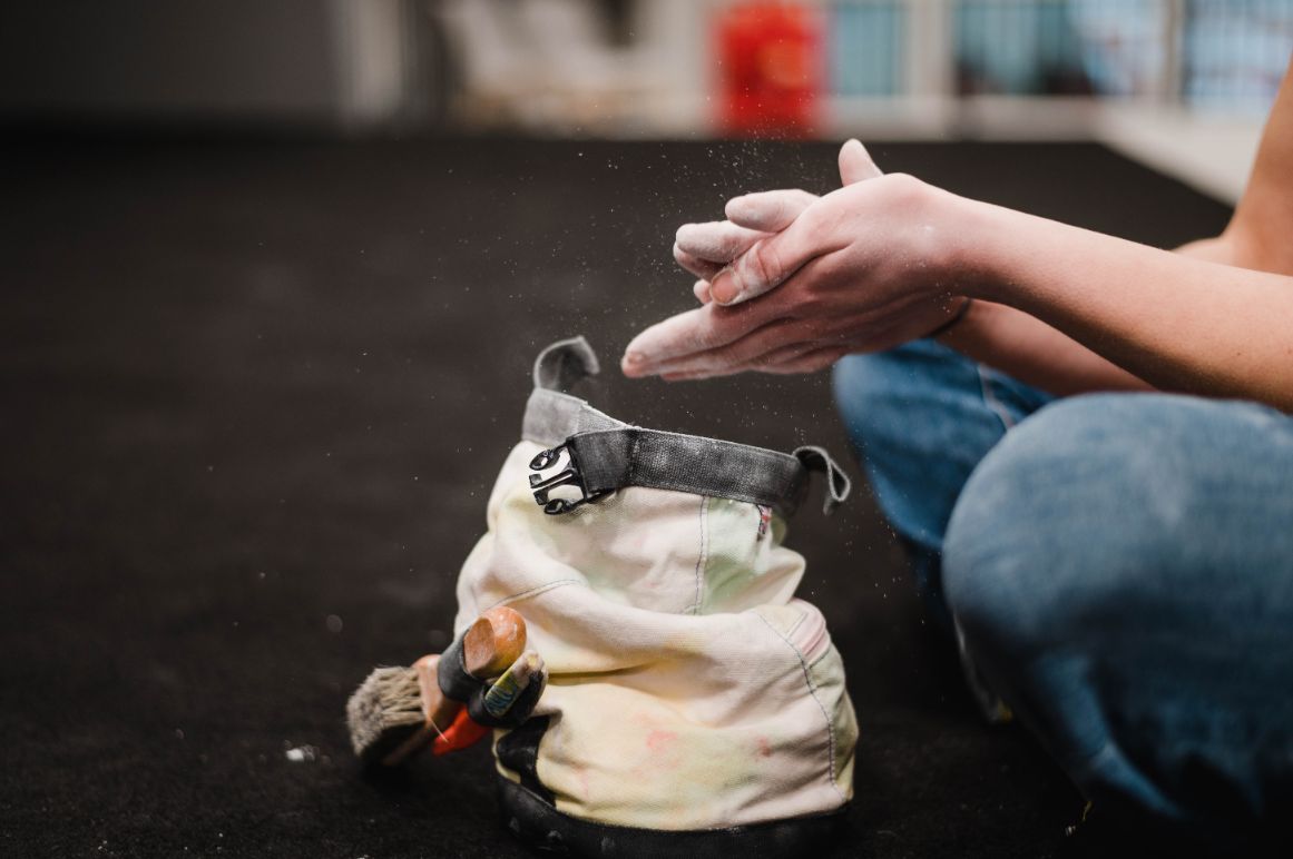 A climbing chalk bag, with hands being dusted with chalk