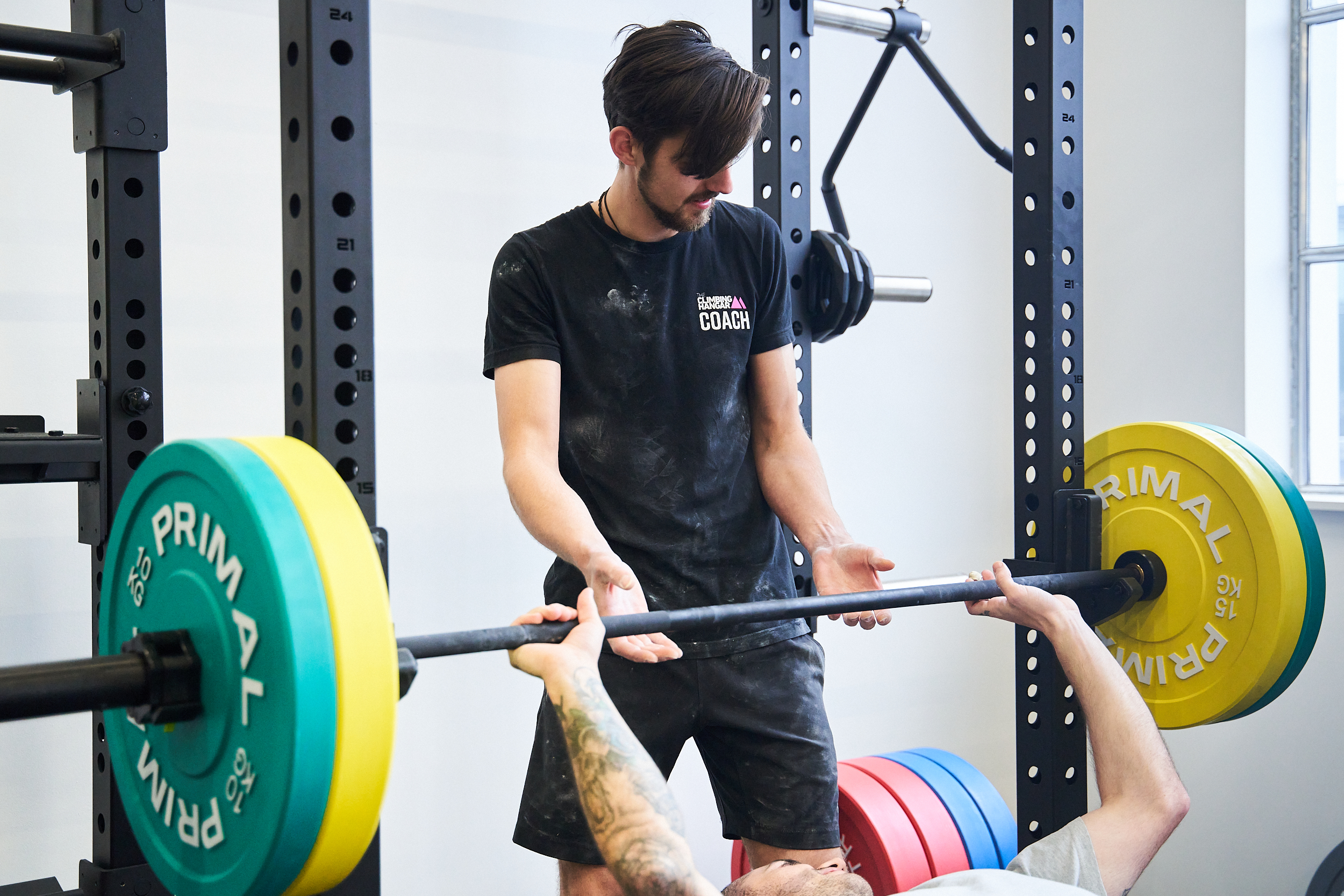 A coach helping someone lift weights