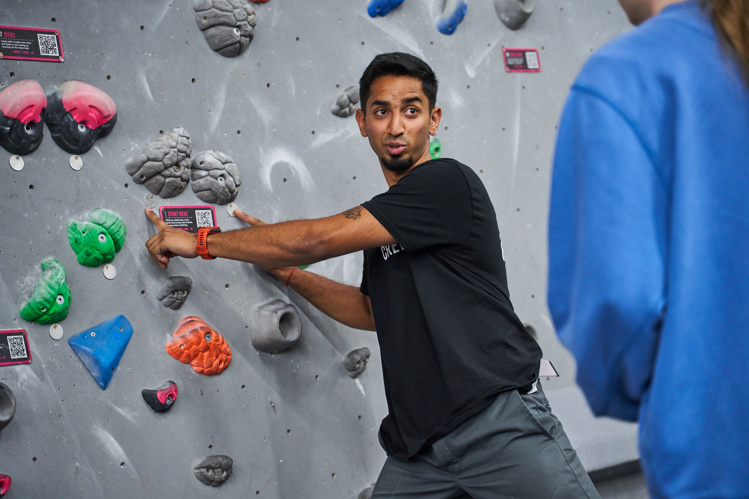 A man pointing out the holds on a wall at The Climbing Hangar